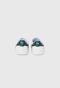 Baskets blanches avec des accents vert foncé et des détails sur les côtés, semelles en caoutchouc et col rembourré, avec un logo au niveau du talon.