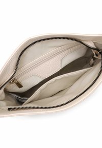 Beżowa skórzana torebka, wnętrze z kieszenią na zamek i dwoma otwartymi przegródkami. Fakturowana podszewka i kontrastujący czarny zamek.