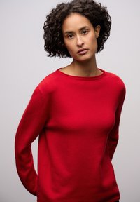 Czerwony sweter z wełny o okrągłym dekolcie, długich rękawach i gładkiej fakturze. Charakteryzuje się luźnym krojem i subtelnymi detalami szwów.