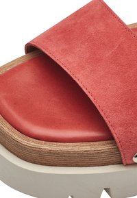 Sandal in suede rosso a pianta scivolosa con soletta in pelle, dettagli in legno e una suola chunky beige testurizzata con leggere scanalature.
