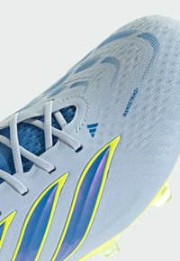Chaussure de football Adidas bleu clair avec lacets blancs, rayures bleues et jaunes, dessus texturé et marquage "NANOSTRIKE".