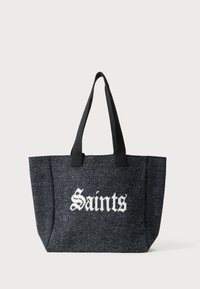 Czarna torba z filcu w ciemnoszarym kolorze z czarnymi uchwytami i białym napisem "Saints". Kwadratowy kształt, teksturowana powierzchnia oraz pojemne wnętrze do przenoszenia rzeczy.