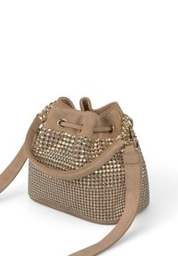 Bolso de cubo beige con tachuelas en tono dorado, acabado en ante, correa de hombro ajustable y cierre de cordón, texturizado con una superficie lisa.