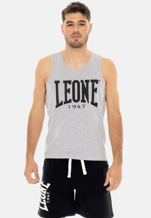 Man draagt een grijs mouwloos shirt en zwarte korte broek, beide bedrukt met "LEONE 1947", staand tegen een effen lichte achtergrond.