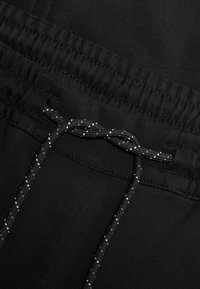Zwarte sportieve shorts met een elastische tailleband en een gemêleerd zwart-wit trekkoord. Gladde stof met minimale details.
