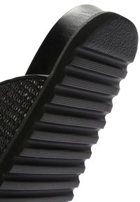 Zwarte slip-on sandaal met een geweven bovenkant en een gevormde rubberen zool met geribbelde details voor grip.