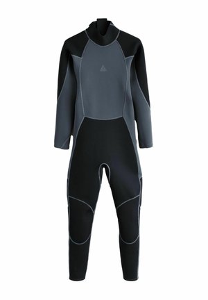 Junger männlicher Surfer in schwarzem Neoprenanzug, der barfuß am Strand entlanggeht und ein türkisfarbenes Surfbrett nahe den Wellen hält.