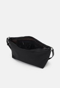 Sac en tissu noir de forme rectangulaire, avec une fermeture éclair sur le dessus et une sangle réglable ; il possède un intérieur texturé et un compartiment spacieux.