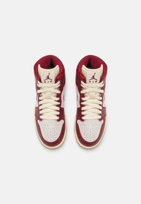 Wysokie trampki w kolorze czerwonym i kremowym, z teksturowaną skórzaną cholewką, perforowanym noskiem, płaskimi sznurowadłami i formowanym logo na języku.
