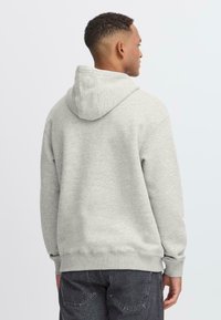 Gray hoodie made of soft fabric, featuring a drawstring hood, ribbed cuffs, and hem. The design is simple with no prominent patterns.