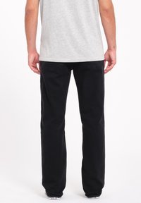 Sorte bomuldsjeans med lige ben, fem-lomme stil og diskrete stikninger. Bæres med en grå T-shirt.