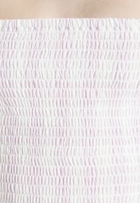 Top tubo franzido em branco e lavanda clara. Apresenta um padrão texturizado com tecido franzido e elástico para maior conforto e ajuste.