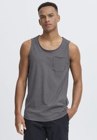Graues Baumwoll-Tanktop mit rundem Halsausschnitt und einer Brusttasche, ausgestattet mit einem entspannten Schnitt und glatter Textur. Schlichtes Design.