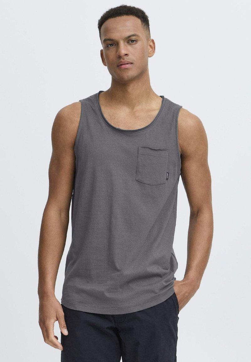 Graues Baumwoll-Tanktop mit rundem Halsausschnitt und einer Brusttasche, ausgestattet mit einem entspannten Schnitt und glatter Textur. Schlichtes Design.