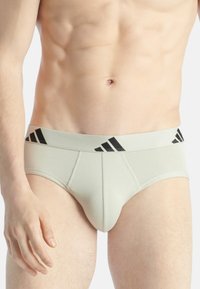 Herrenslips aus leicht beigem Stoff. Mit einem schwarzen elastischen Bund, der drei Streifen aufweist, und flachen Nähten für zusätzlichen Komfort. Klassische Slip-Form.
