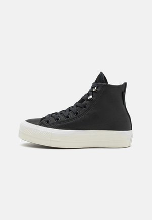Sneaker alte nere con tomaia in pelle testurizzata, suola in gomma bianca e punta rotonda classica. Presentano lacci neri e occhielli in argento.