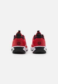 Rote Sportschuhe mit strukturiertem Obermaterial, schwarzen Akzenten und weißen Sohlen. Mit einem Logo auf der Rückseite und kleinen Belüftungslöchern für Atmungsaktivität.