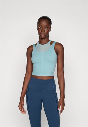 Un crop top de sport bleu clair avec un détail en maille et des bretelles larges, associé à un legging taille haute bleu foncé, les deux portant les logos Nike.