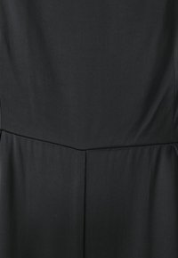 Svart klänning med en jämn, matt yta. Har en figursydd bodice, en yoke-stil söm och en mjukt rynkad nederdel. Minimalistisk design.