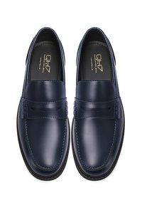 Mocassini in pelle blu navy con finitura lucida, caratterizzati da un accento cucito e una fascetta decorativa sulla tomaia. Suola in gomma resistente.