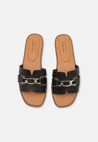 Des sandales à glissière en cuir végan noir avec deux larges lanières et un accent de chaîne métallique. Semelle intérieure rembourrée marron avec détail du logo. Forme de bout carré.