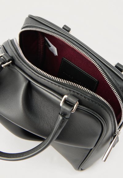 Μαύρη δερμάτινη τσάντα χειρός με διπλές λαβές, ασημένιο φερμουάρ μερικώς ανοιχτό που αποκαλύπτει εσωτερική φόδρα βουργουνδί και εσωτερικές τσέπες.