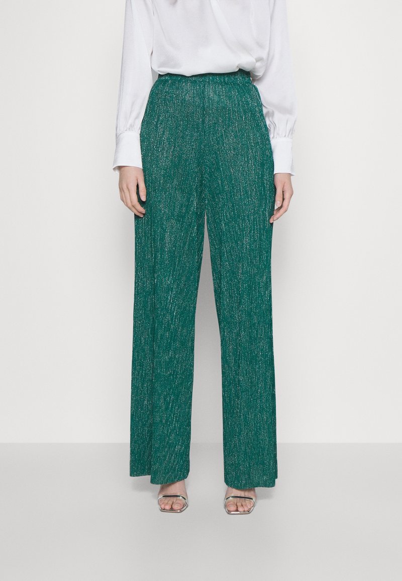 Teal wijde broek met een gestructureerde, glinsterende afwerking. Heeft een hoge taille en een vloeiende silhouet. Gecombineerd met een witte blouse en zilveren sandalen.