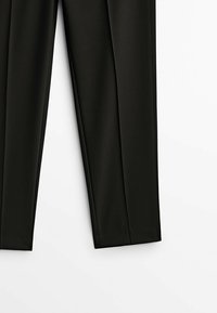 Pantalon noir à jambes droites avec plis à l'avant, présenté à plat sur fond blanc, montrant la moitié inférieure du vêtement.