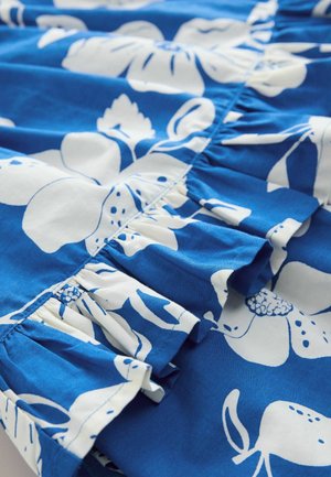 Blauwe stof met grote witte bloempatronen en gathered ruffle-details langs de rand, wat textuur en visuele interesse biedt.