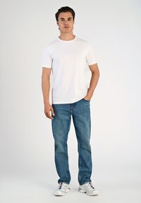 T-shirt bianca a maniche corte abbinata a jeans blu a gamba dritta e scarpe da ginnastica bianche con accenti colorati. Design semplice, vestibilità casual.