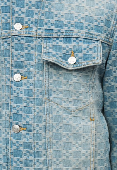 Ανοιχτό μπλε τζιν μπουφάν με ανάγλυφο μοτίβο σκακιέρας, λευκά κουμπιά τύπου snap, τσεπάκι στο στήθος με κουμπί και πορτοκαλί ραφές.