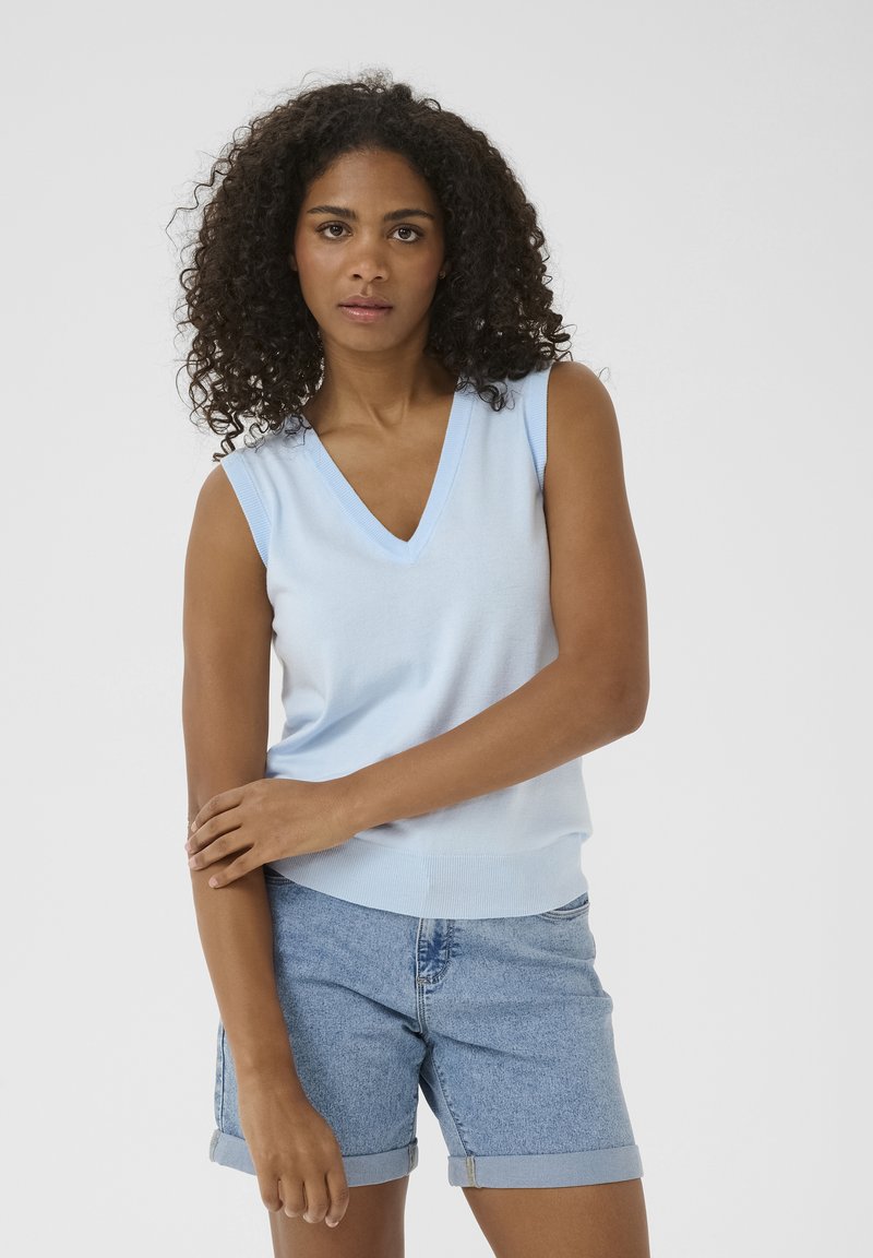 Haut en tricot sans manches de couleur bleu clair avec un col en V, bordure côtelée et silhouette ajustée, associé à des shorts en denim retroussés. Texture lisse.