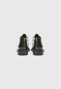 Sleek black leather ankle boots with a glossy finish, round toe, minimal detailing, and a sturdy sole. Back view showcases dual straps.