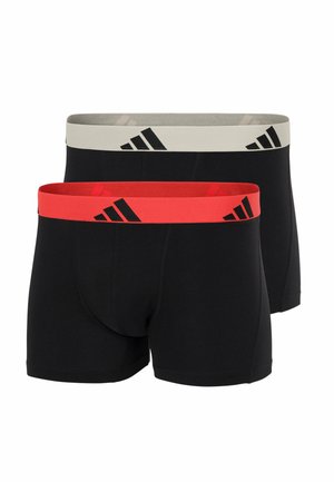 Deux caleçons boxeurs noirs avec ceintures élastiques, l'un rouge et l'autre gris clair, tous deux arborant un logo Adidas noir.