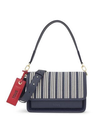 Bolso con rayas azules marino y blancas, con correa desmontable, cierres dorados y una etiqueta rectangular roja etiquetada como "TOUS".
