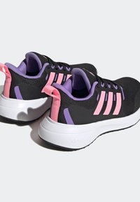 Scarpe da ginnastica nere con tre strisce rosa, dettagli viola, parte superiore in rete, colletto imbottito e suola bianca testurizzata con il marchio "cloudfoam".