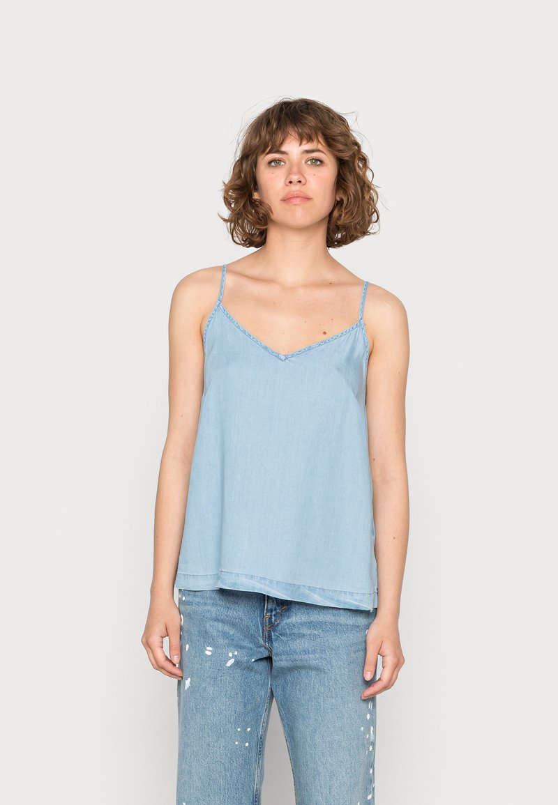 Camisola de ganga azul clara com alças finas, decote em V e costura delicada ao redor do decote. Corte solto com uma bainha reta.