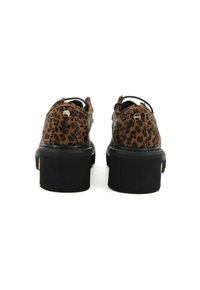 Une paire de chaussures à lacets imprimées léopard avec de grosses semelles noires épaisses, vue de l'arrière sur fond blanc.