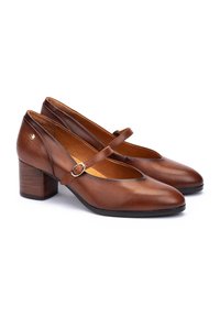 Talons Mary Jane en cuir marron avec un bout arrondi, une sangle de cheville avec une boucle et un talon carré texturé. Fini lisse avec un design minimaliste.