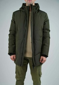 Veste doudoune verte avec fermeture éclair sur le devant, col haut et capuche ajustable. Comprend des poches latérales et une texture matelassée pour l'isolation.