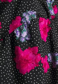 Tissu noir avec des motifs de cœurs blancs, présentant de grandes impressions florales vibrantes en rose et violet. Texture lisse avec des détails de design en couches.