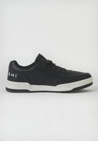 Sneakers sintetice negre cu o textură netedă, având o talpă din cauciuc alb și un logo pe toc. Design low-top cu sistem de închidere tip șiret.