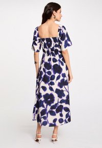 Robe maxi avec un décolleté carré, des manches courtes bouffantes et un dos smocké. Dotée d'un motif floral bleu marine sur un fond crème.