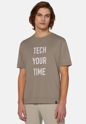 Koszulka bawełniana krótki rękaw w odcieniu beżowym z dużym białym napisem "TECH YOUR TIME". Posiada okrągły dekolt oraz luźny krój. Brak widocznych wzorów.