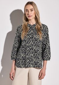 Camicia button-up nera e crema con un motivo ondulato, dotata di colletto tondo e maniche a tre quarti. Tessuto morbido e leggero.