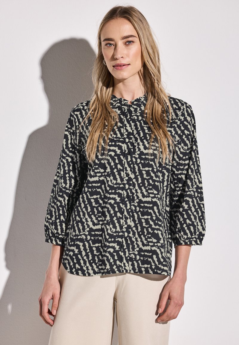 Camicia button-up nera e crema con un motivo ondulato, dotata di colletto tondo e maniche a tre quarti. Tessuto morbido e leggero.