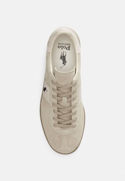 Μπεζ πάνινο παπούτσι με εκρού λεπτομέρειες, επίπεδα κορδόνια και λογότυπο στο πλευρό. Διαθέτει επενδεδυμένο πέλμα και υφασμένο καουτσούκ σόλα.