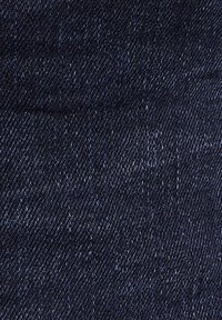 Dark blue denim fabric with a fine diagonal weave, featuring a smooth texture and subtle variations in shade. No visible patterns or hardware.