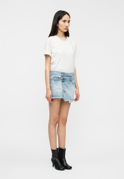 Λευκό κοντομάνικο μπλουζάκι συ νδυασμένο με ανοιχτό μπλε τζιν μίνι φούστα με ξεφτισμένα τελειώματα και θηλιές για ζώνη, ολοκληρωμένο με μαύρα μποτάκια αστραγάλου.