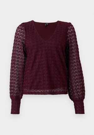 Långärmad burgundy spetsblus med V-ringning, puffiga genomskinliga ärmar och texturerad geometrisk mönstring på kroppen och ärmarna.